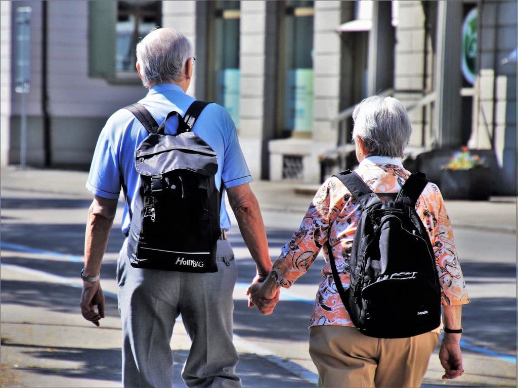 An older couple walks hand in hand.