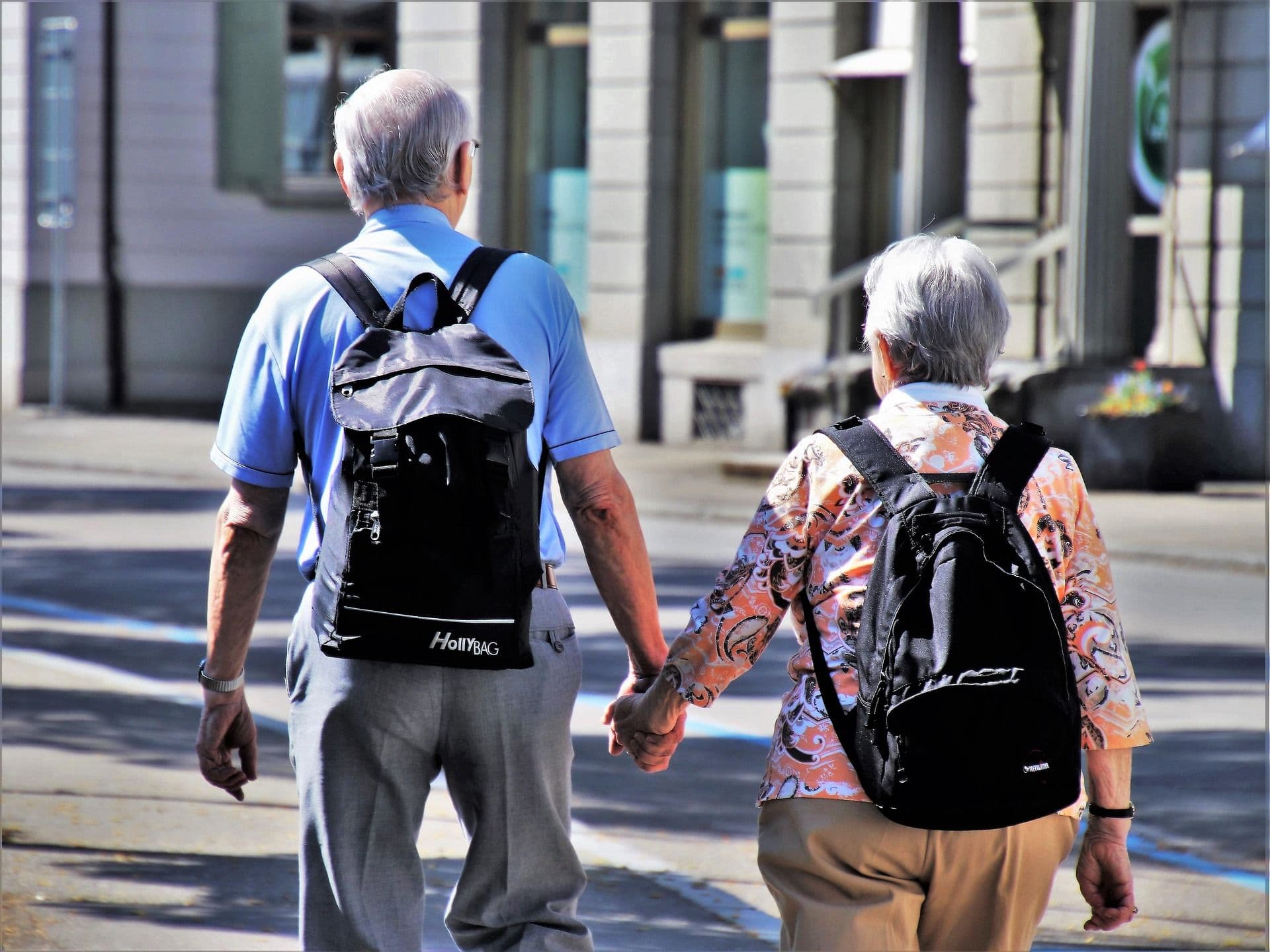 An older couple walks hand in hand.